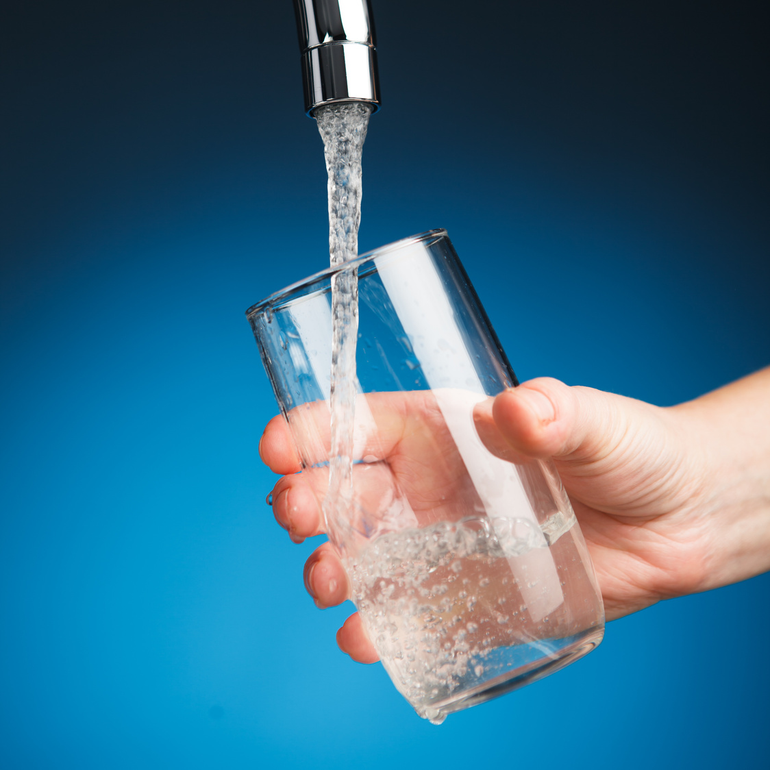 hand pouring a glass of water from filter tap