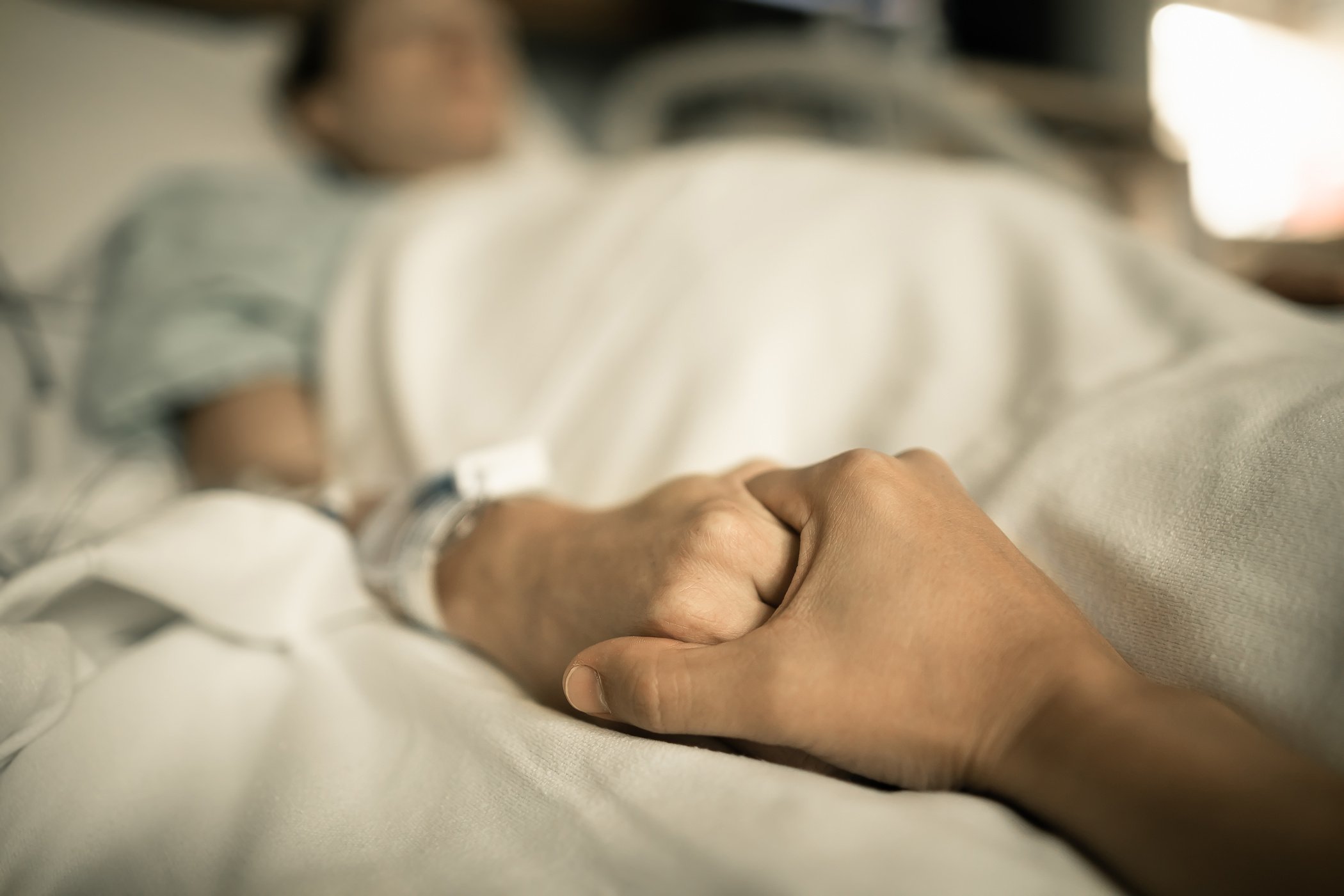 Man holding woman hand in hospital bed. Holding hands in hospital bed